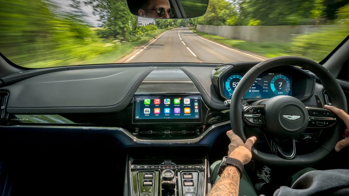Someone driving an Aston Martin using CarPlay Ultra