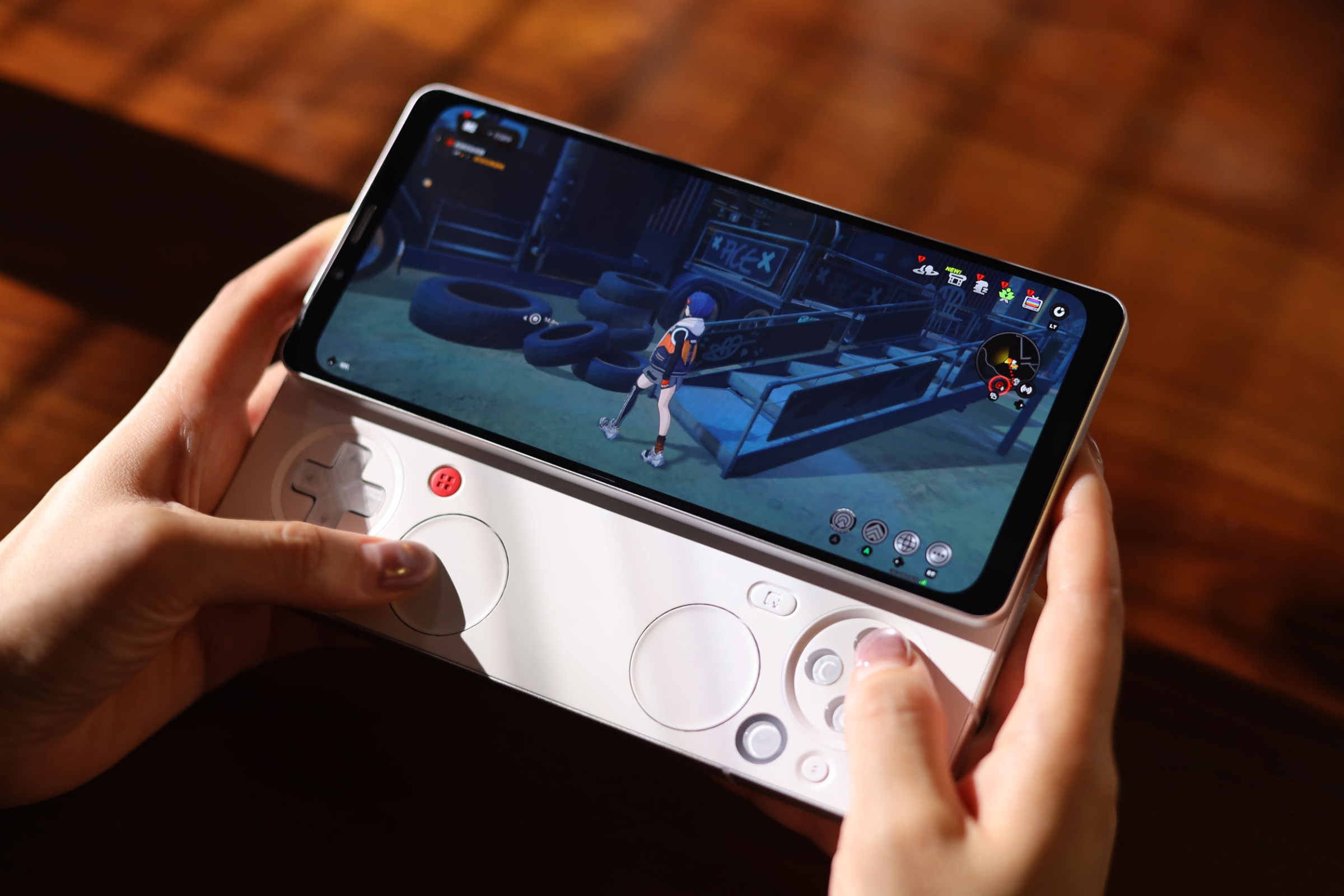 A person holds the Ayaneo Pocket Pay phone in two hands with its gaming controls extended.