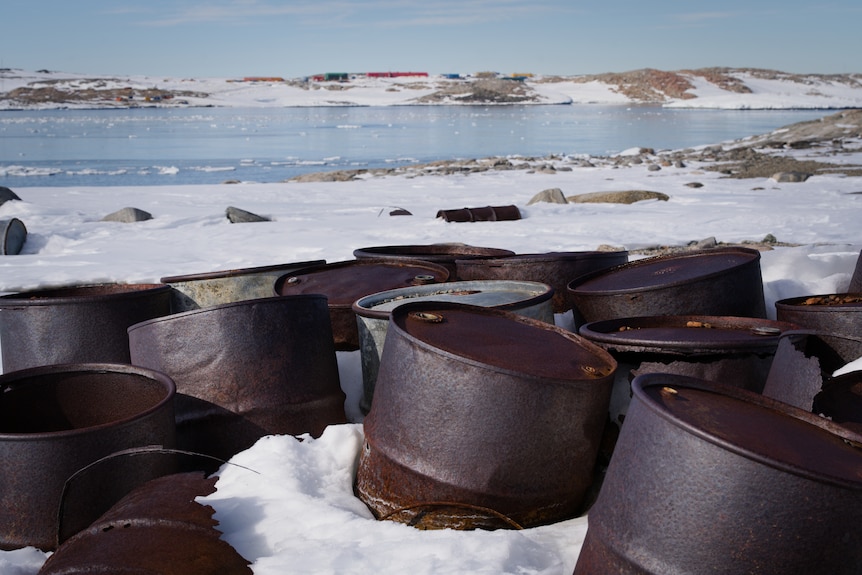 Rusted barrels in foreground of an icy wilderness environment.
