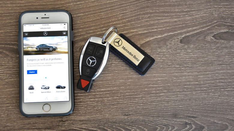 A Mercedes Benz car key fob next to an iPhone