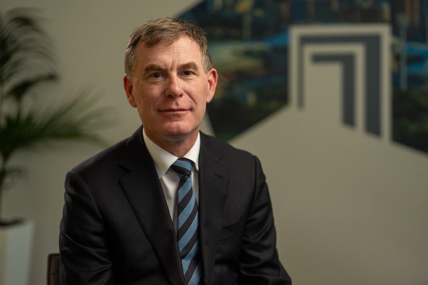 Man in a black suit with a striped blue tie.