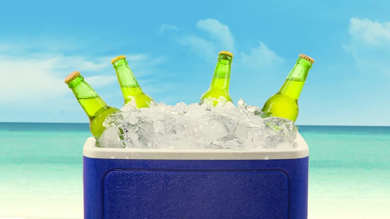 Chilly bin on a beach with drinks in it.