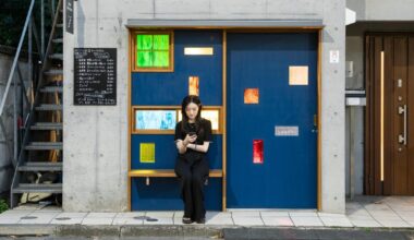 colored glass apertures reveal lively tokyo bar through bright blue entrance