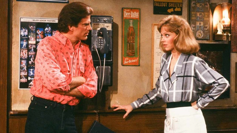 Ted Danson as Sam folds his arms next to Shelley Long as Diane in Cheers