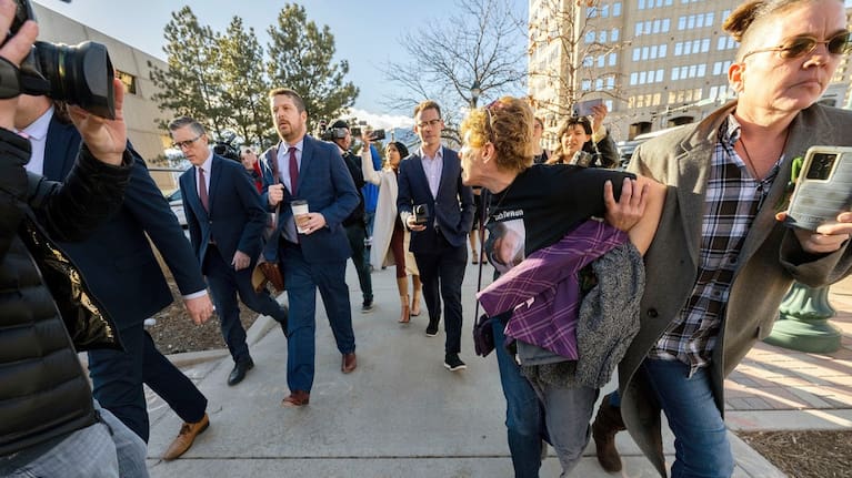 Chrystina Page, right, holds back Heather De Wolf, as she yells at Jon Hallford, left, the owner of Back to Nature Funeral Home, as he leaves with his lawyers following a preliminary hearing outside the El Paso County Judicial Building, in Colorado Springs, Colorado. (Source: The Gazette via AP)
