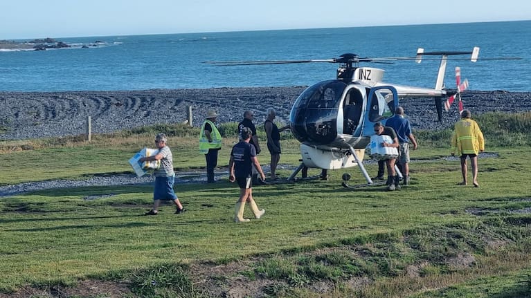 Community members unload supplies from a helicopter at Ngawi golf course.