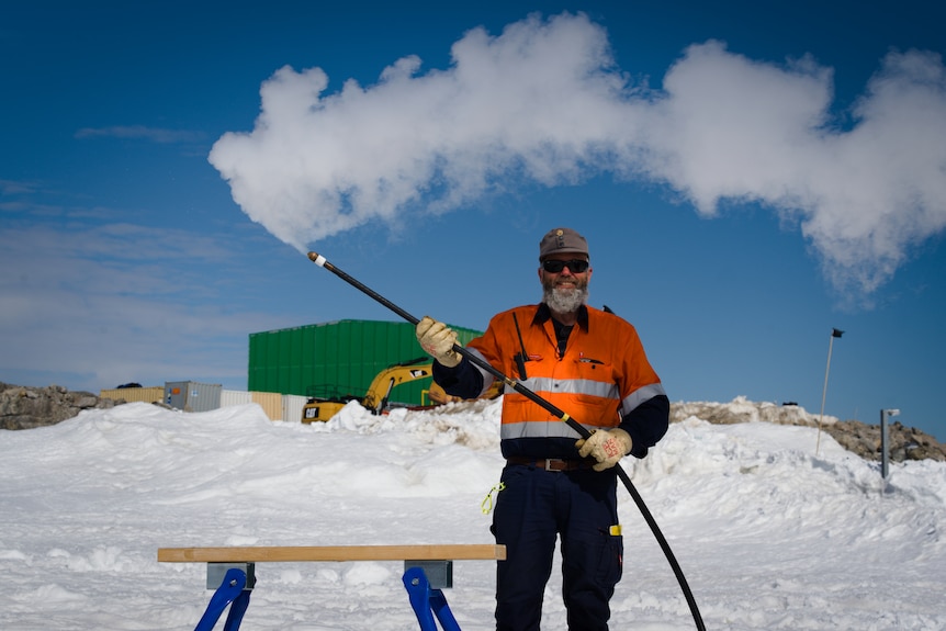 A man in a snowy environment holds a steam drill.