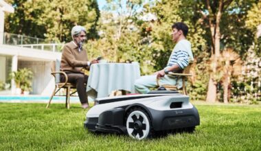 Robot lawnmower on a lawn with people in the background.