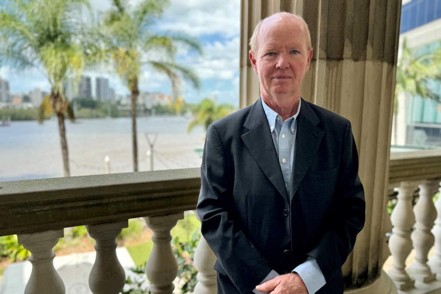 A man standing before a pole.