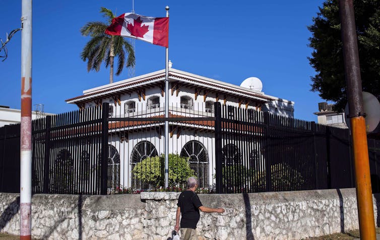 a building flying a canadian flag behind a wrought-iron fence