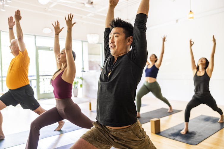 Diverse group of students doing crescent lunge pose during a yoga class.