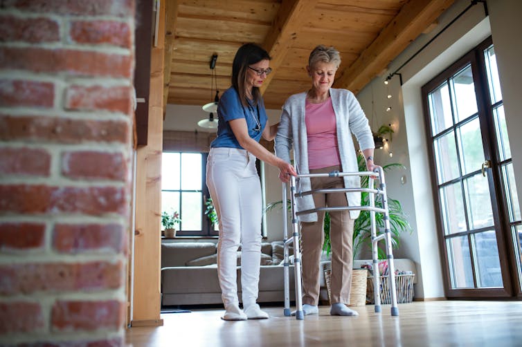 A health-care worker with a women using a walker
