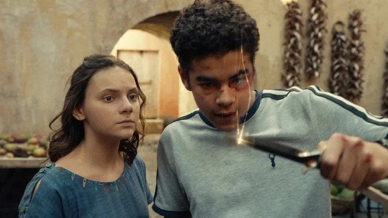 Lyra standing next to Will holding a metal object in His Dark Materials