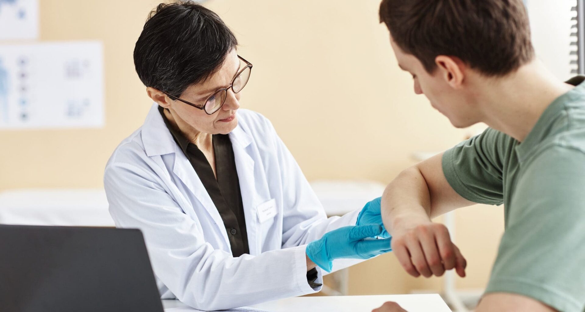 Portrait of mature female doctor inspecting patient with skin rash during consultation in dermatology clinic