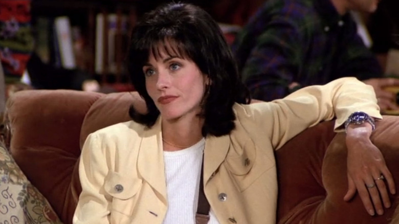 Courteney Cox as Monia Geller, lounging on the couch in Central Perk, on Friends.