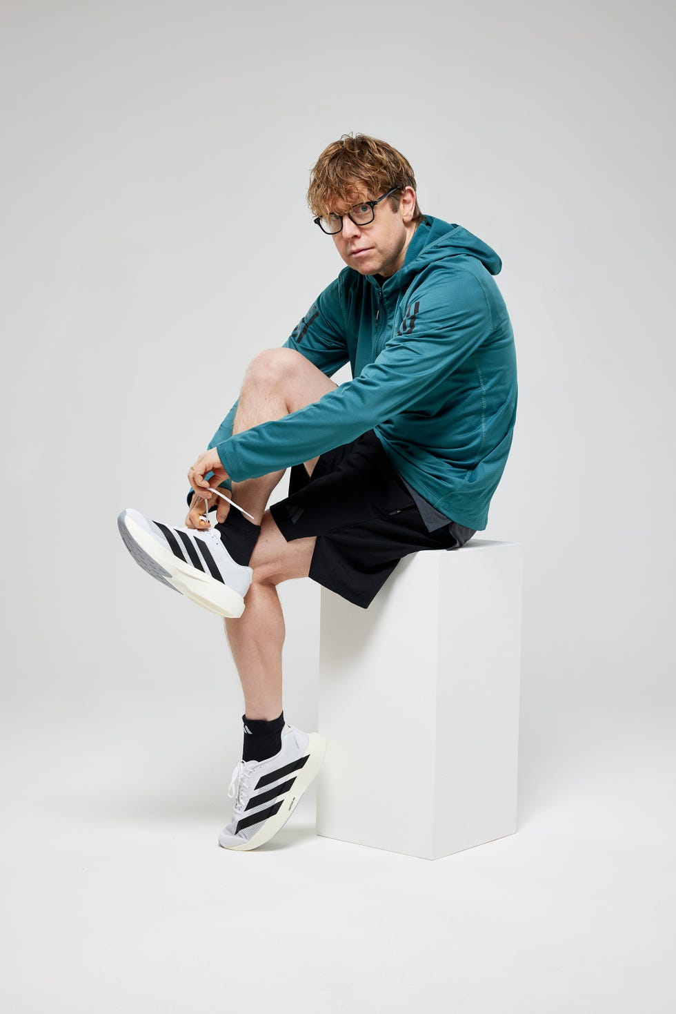 person sitting on a pedestal putting on athletic shoes