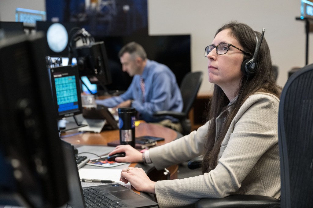 Artemis II Science Officers, Kelsey Young, foreground, and Trevor Graff, work at the Science console in the Mission Control Center at NASA’s Johnson Space Center in Houston. The science officer will sit on console with other flight controllers in the flight control room of mission control during Artemis II. (NASA/James Blair)