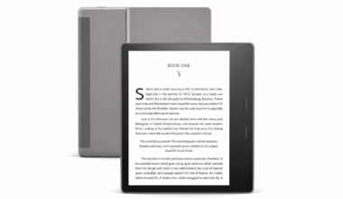 A black e-reader displaying BOOK ONE on its screen, with a gray cover partially visible behind it, set against a clean white background.