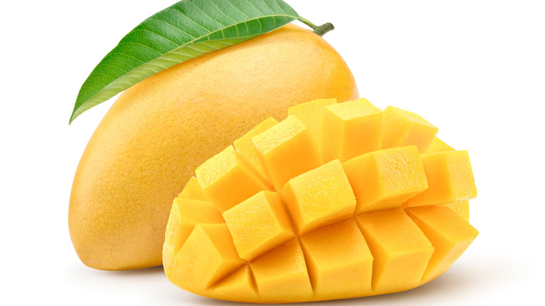 A whole mango and a cut mango on a white background