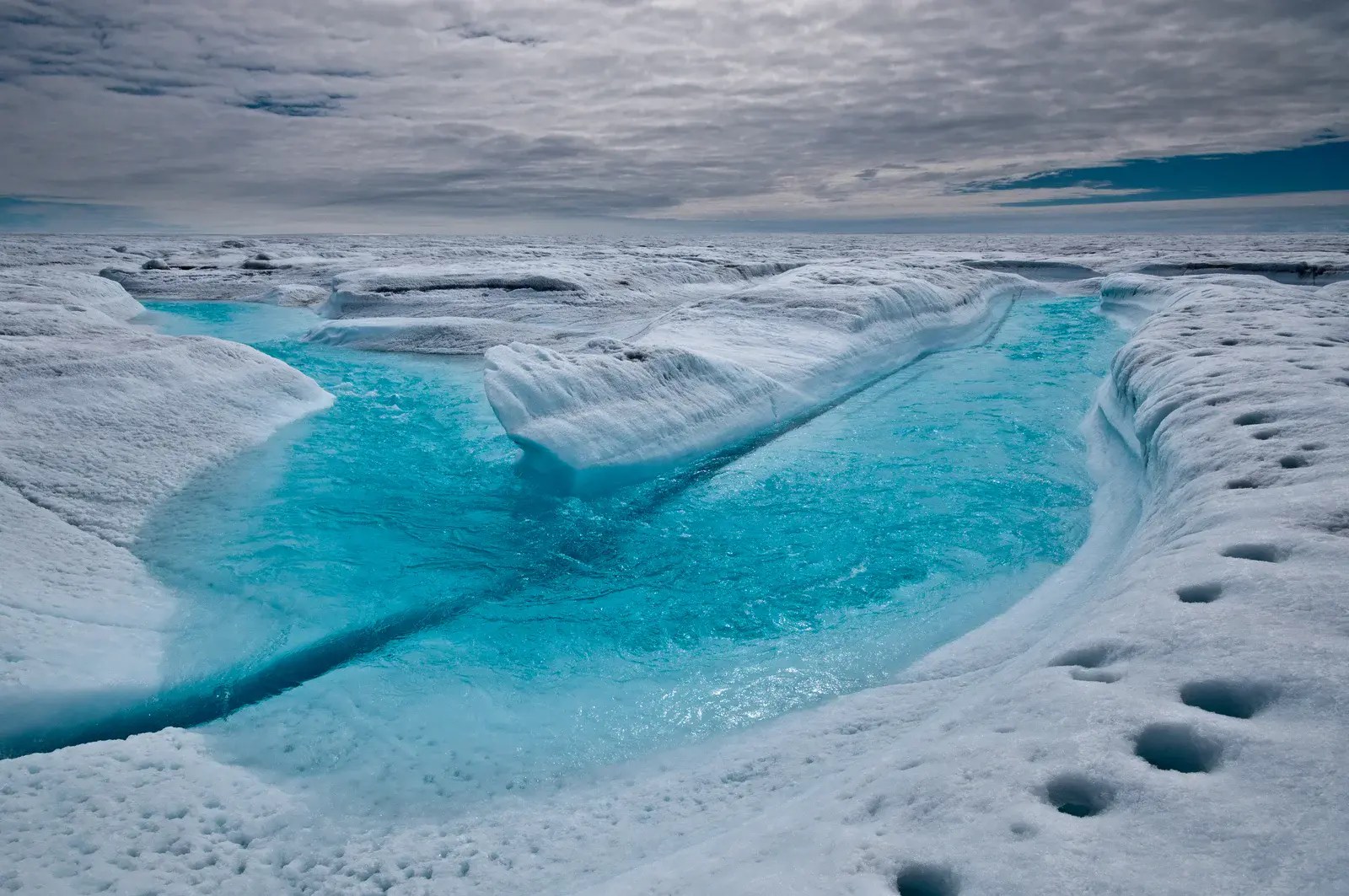 A blue stream meanders through an ice landscape.