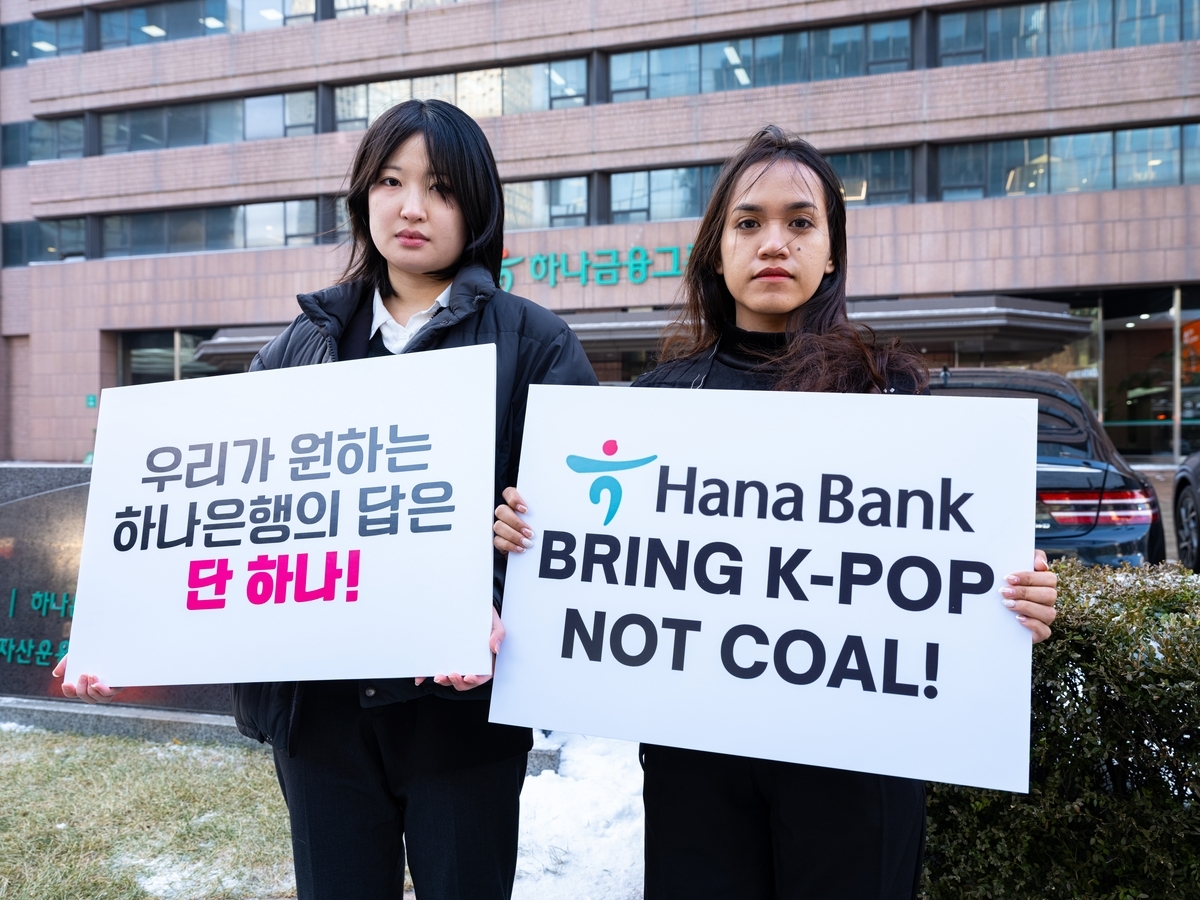 Lee Da-yeon (left) and Nurul Sarifah hold signs demanding that Hana Bank cease funding nickel projects on Feb. 2. (Kpop4Planet)