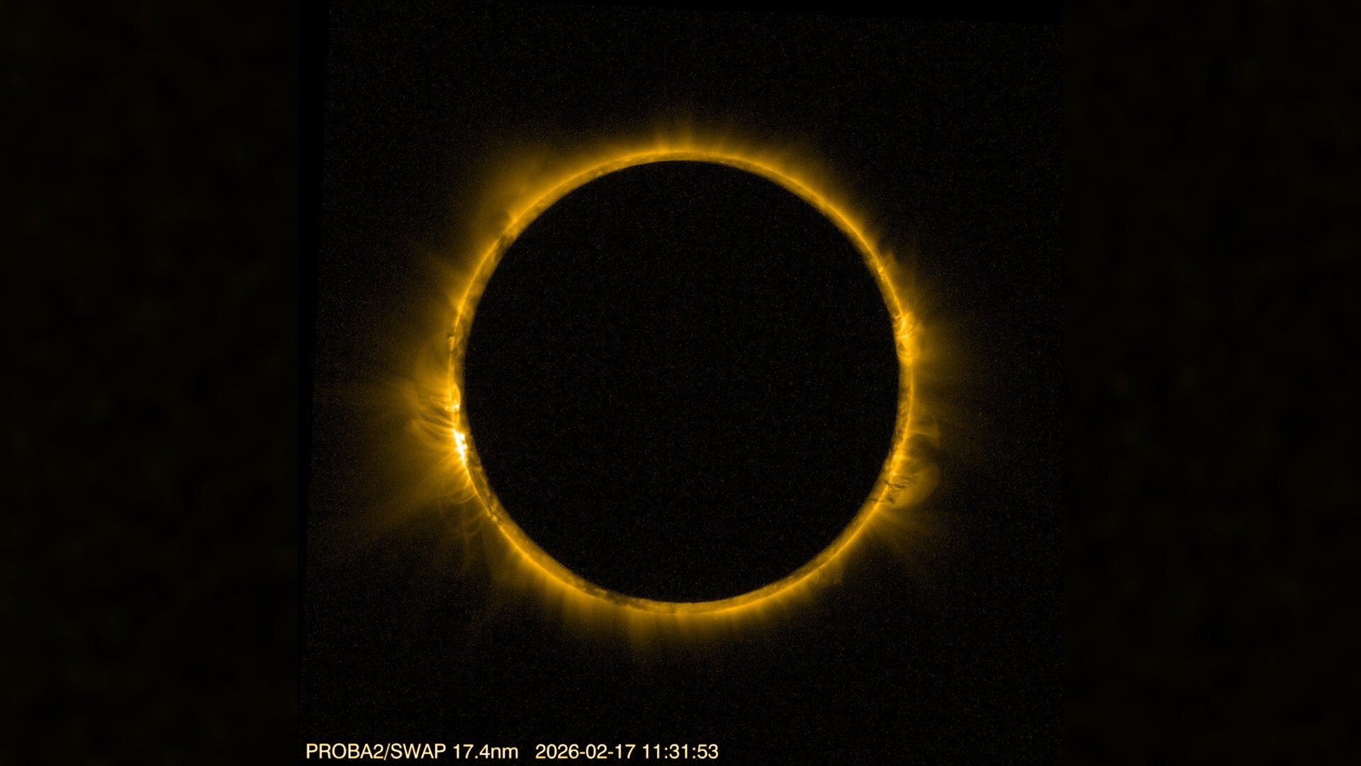detailed view of the sun blocked by the moon in the center, creating a dramatic ring of fire against a black background. The sun's corona is visible around the edge of the moon.