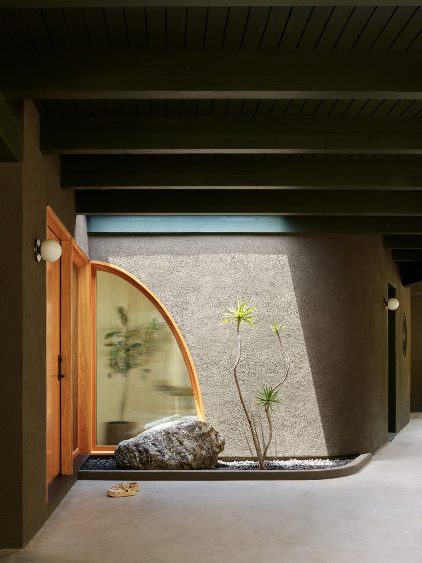 Entrance to a renovated mid-century home with an arc-shaped with and a skylight