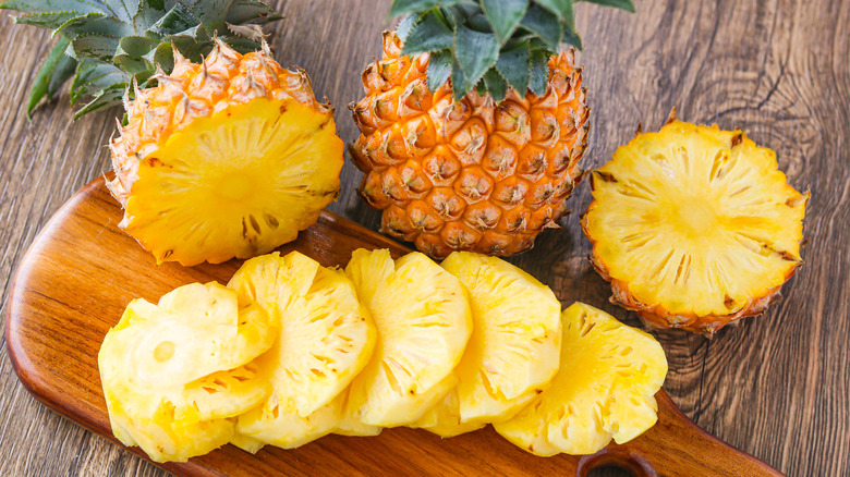 Whole and sliced pineapple on a cutting board
