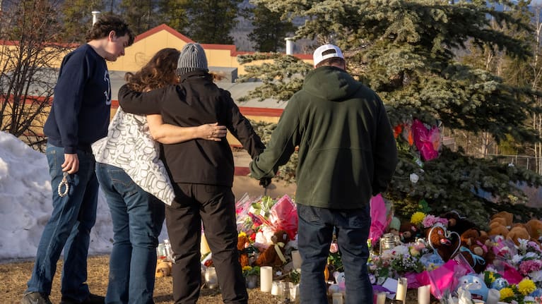 Residents hug as they place flowers at a memorial for the victims of Tuesday's mass shooting in Tumbler Ridge, British Columbia, Canada.