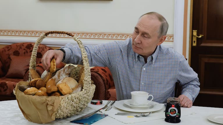 Russian President Vladimir Putin tries pastries from the Mashenka bakery in Moscow on December 20, 2025, after the owner asked him about tax reforms at his annual call-in show.