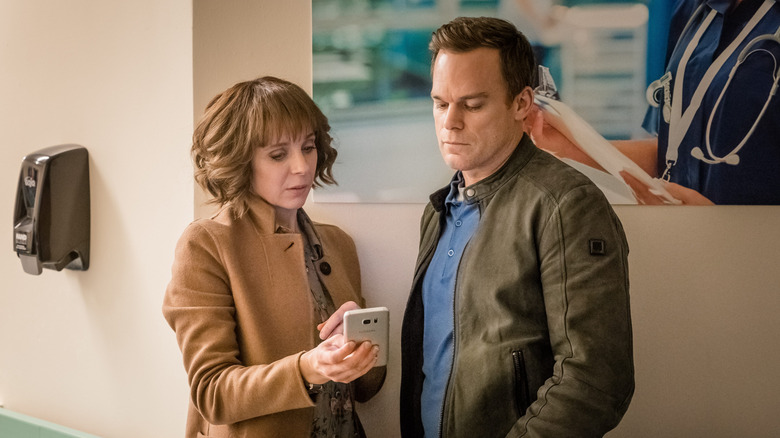 Amanda Abbington and Michael C. Hall as Sophie Mason and Tom Delaney, looking at a phone together in Safe