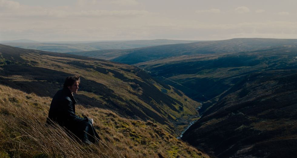 person sitting on a hillside overlooking a valley