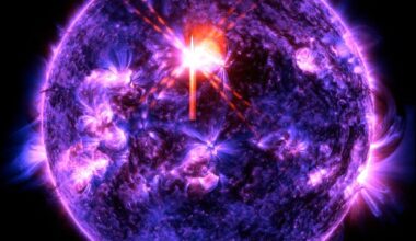 The Sun is blue, purple, and black with a bright purple line surrounding it. Scattered across it are some brighter purple spots where there is higher activity. Just above center is a bright red and white X: This is the solar flare.