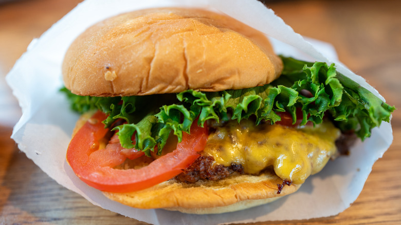 ShackBurger from Shake Shack in paper sleeve with cheese, lettuce, and tomato