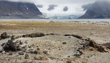 Remains of a 17th-century blubber oven at Smeerenburg with glacier and Arctic mountains in Svalbard.