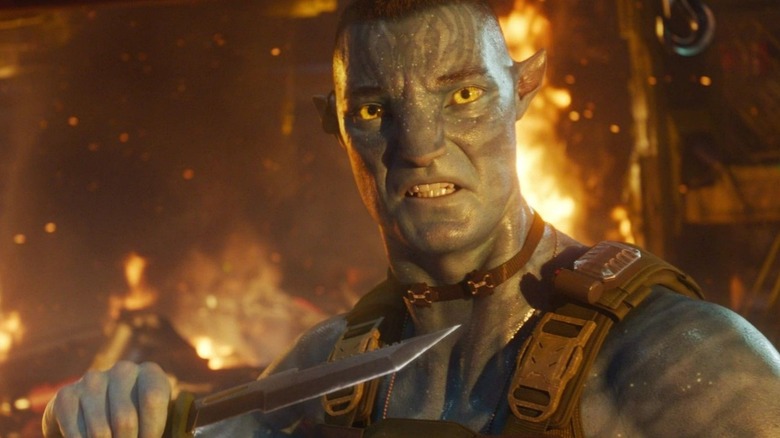 Quaritch in a fiery place holding a knife in Avatar: Fire and Ash