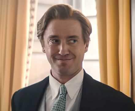 Tom Felton's Archibald smiling and looking to the side in Fackham Hall