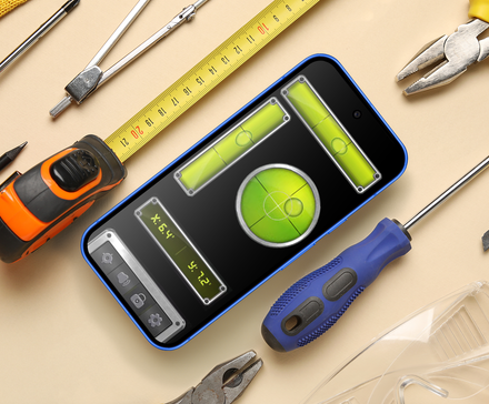 Top-down view of a smartphone displaying a bubble level app, surrounded by traditional hand tools like pliers, a measuring tape, and screwdrivers.
