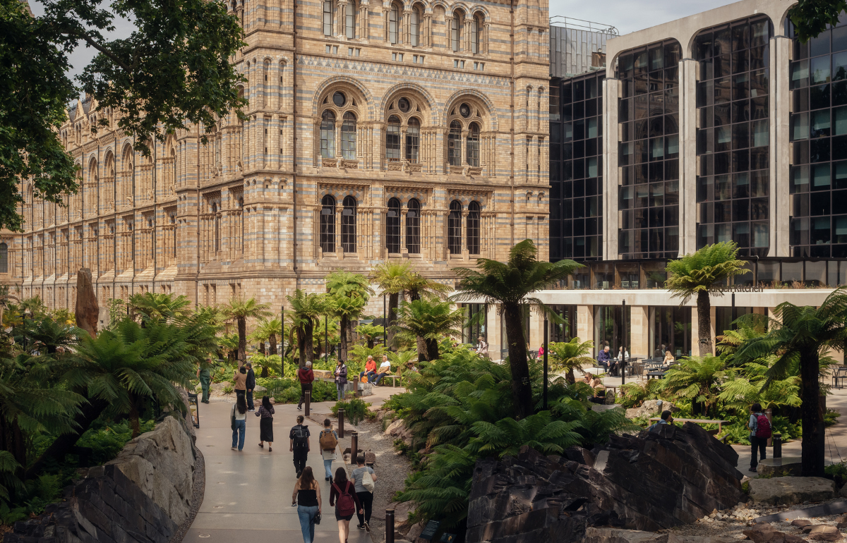 Pale stone older building with glass arch windows and a modern black glass building attached