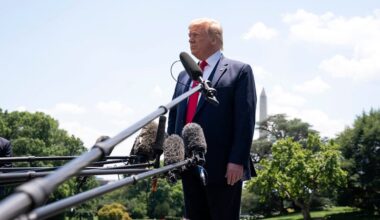 President Donald Trump standing behind   a microphone in an outdoor setting.