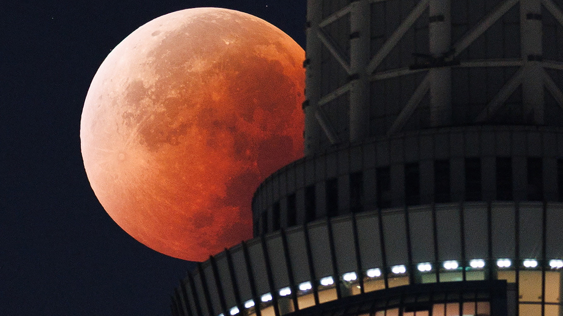 A red full moon is shown during an eclipse behind a tower in Japan.