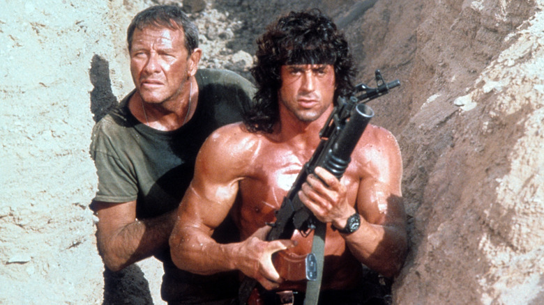 Richard Crenna as Colonel Sam Trautman and Sylvester Stallone as John Rambo, brandishing a grenade launcher are hunkered down in a trench in Rambo III