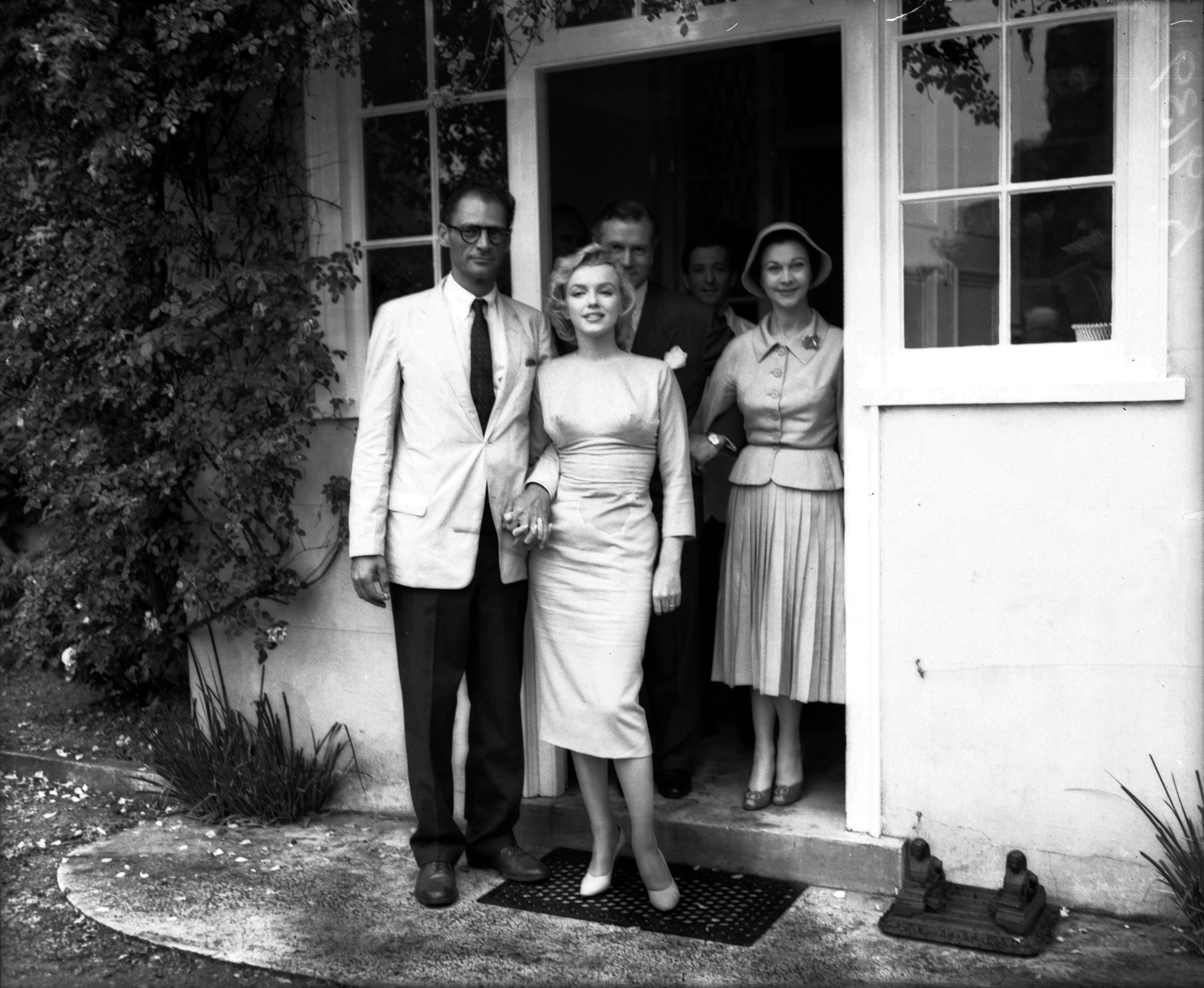 Marilyn Monroe and husband Arthur Miller holding hands with Sir Laurence Olivier and Lady Olivier (Vivien Leigh) visible behind them at Parkside House.