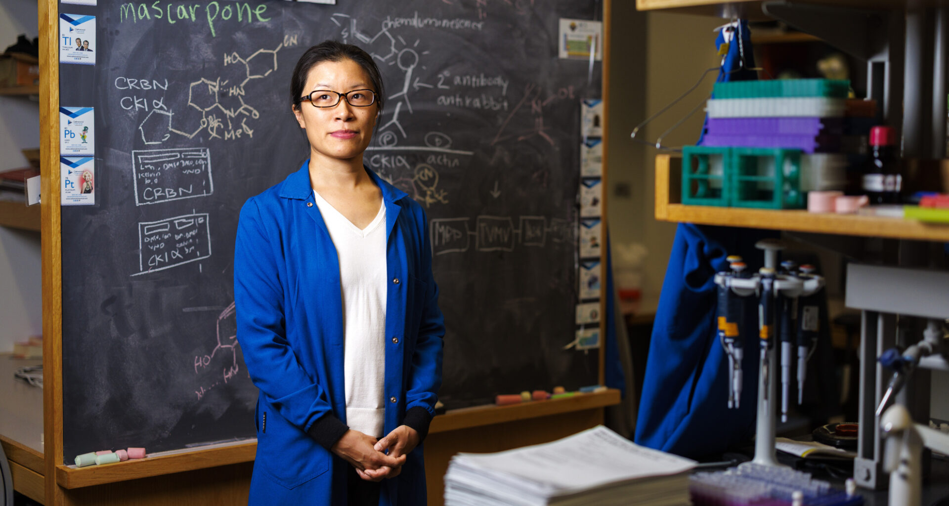 Christina Woo standing in front of a chalkboard.