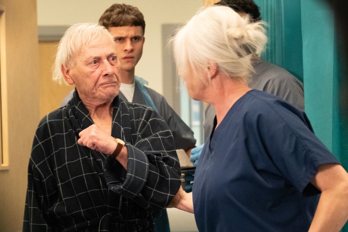 Jacob looks towards Dr Todd speaking inappropriately to a patient in a scene from Emmerdale