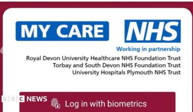 The image shows a screen shot shows the mobile log in page of the new app 'My Care'. It is a red page with white boxes and the blue NHS logo.