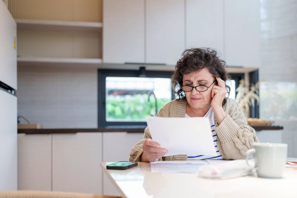 Stressed and Worried Senior Woman Calculating Domestic Expenses, Sitting at Dining Table in the kitchen, People, Accounting, Finances, Family Budget and Financial Issues Concept.