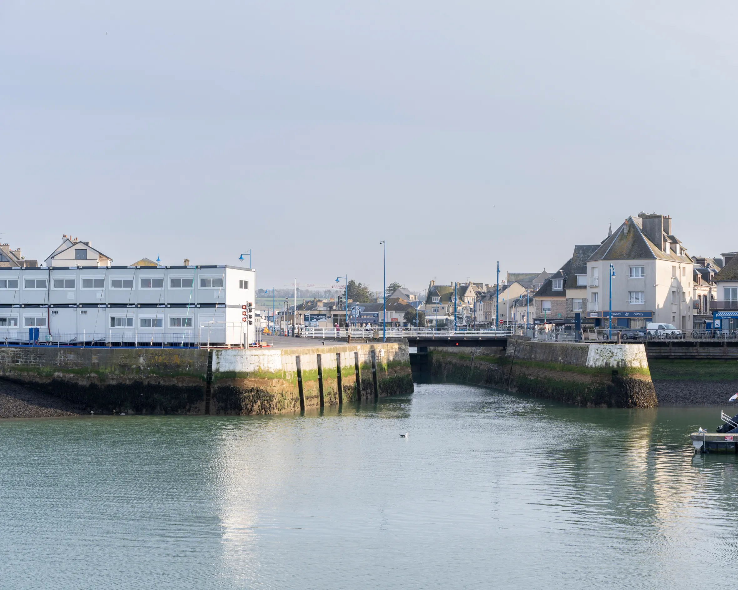 A port in Port en Bessin, France, with buildings on both sides of a narrow waterway.