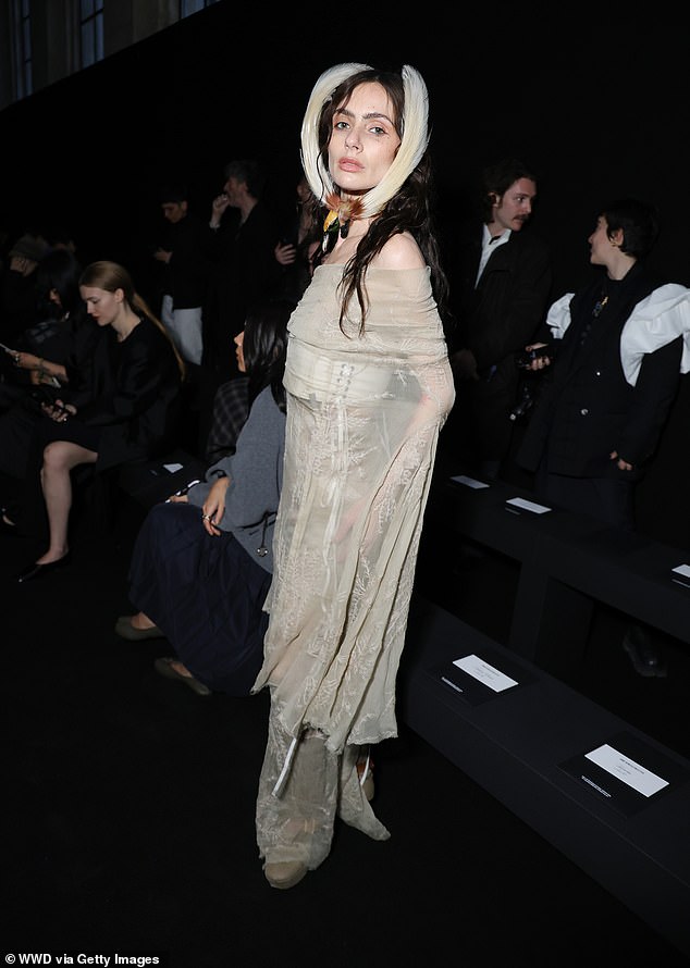 Dracula star Zoe Bleu put on a dramatic display in a sheer off-shoulder gown and matching a hair fascinator