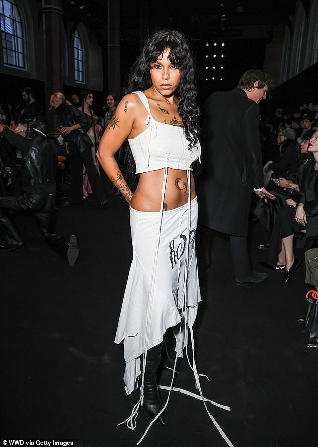 Dominican rapper Tokischa showcased her incredibly flat abs in a white crop top and a matching draped low-rise skirt and pointy leather boots